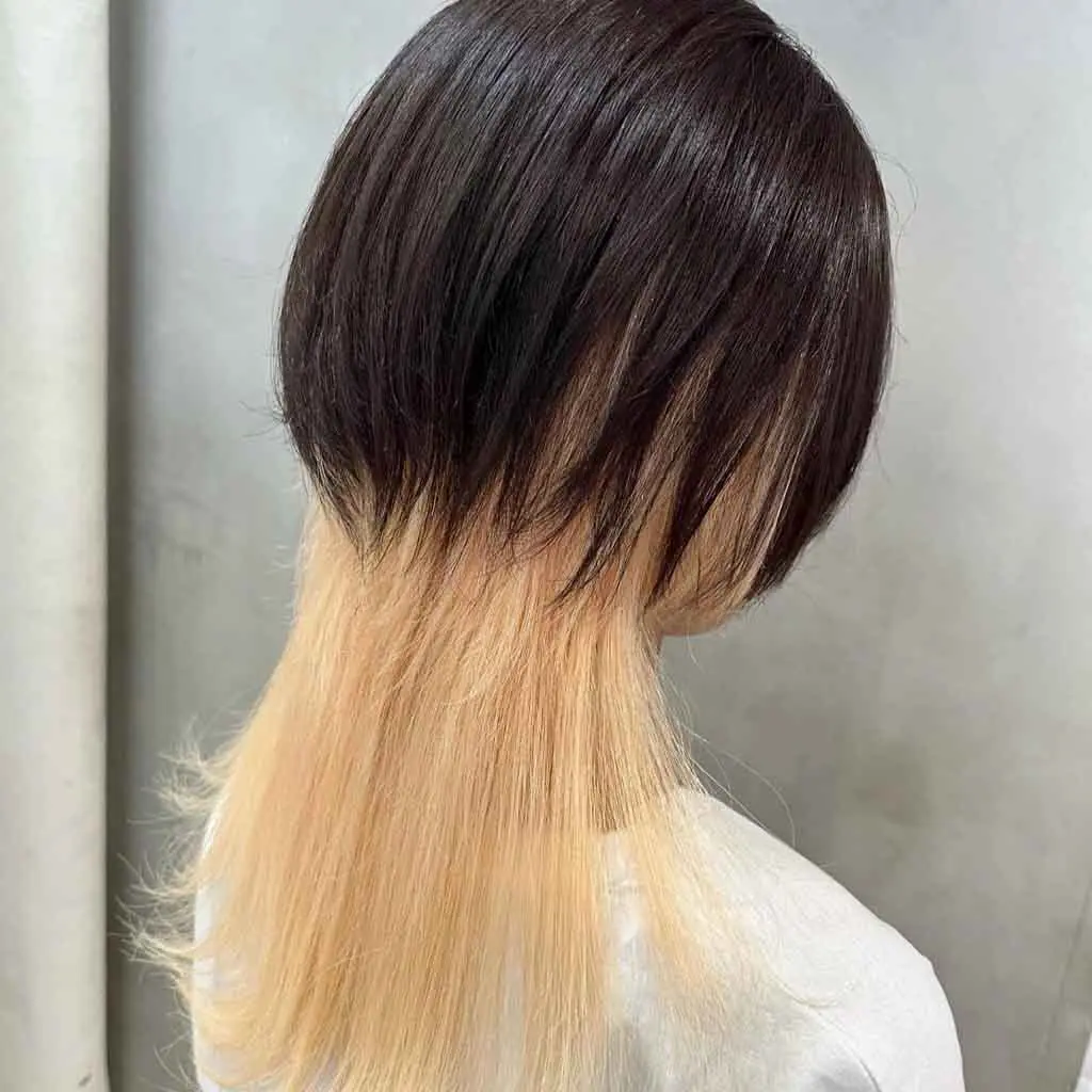 Woman flaunting a duo-toned midnight black and super light blonde choppy octopus wolf cut, highlighting a bold, edgy contrast