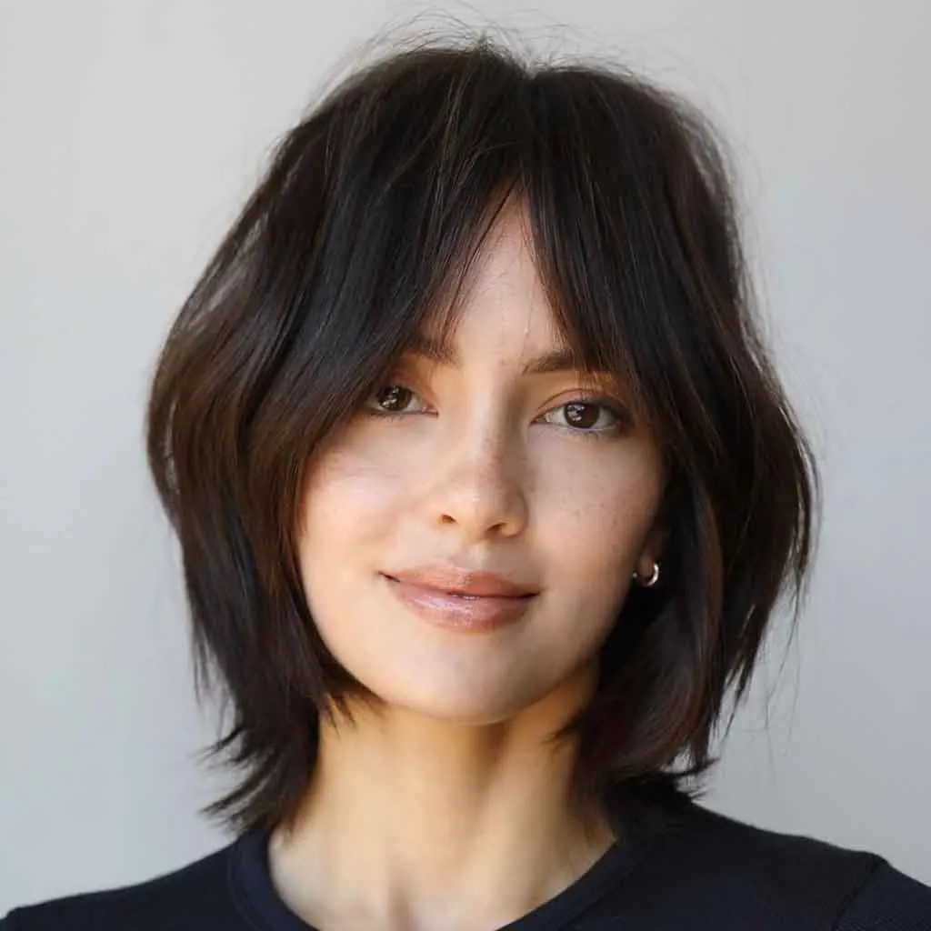 Woman rocking a face-framing black coffee bob wolf cut with curtain bangs, achieving a flattering and sophisticated look