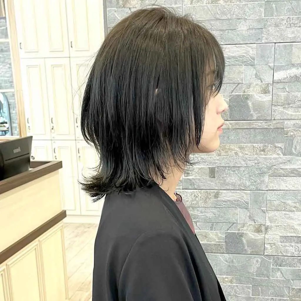 Woman flaunting a short crow black bob wolf cut with long choppy bangs, creating a modern, edgy appearance