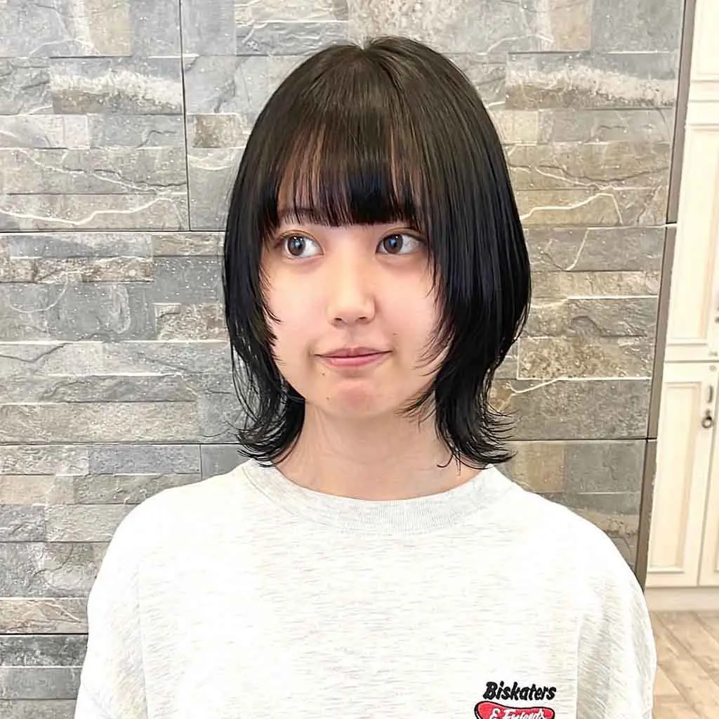 Woman showing off a short Korean wolf cut with choppy bangs, achieving a trendy and effortless style