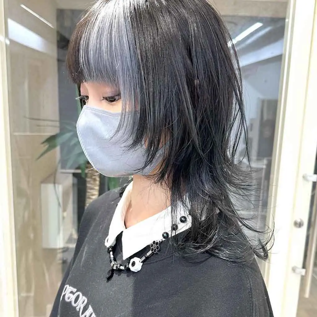 Woman flaunting a slate black medium jellyfish wolf cut with blunt choppy bangs and ash grey highlights, featuring a bold contrast