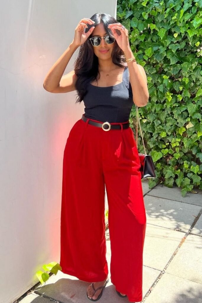 black tank top tucked into high waisted red pants