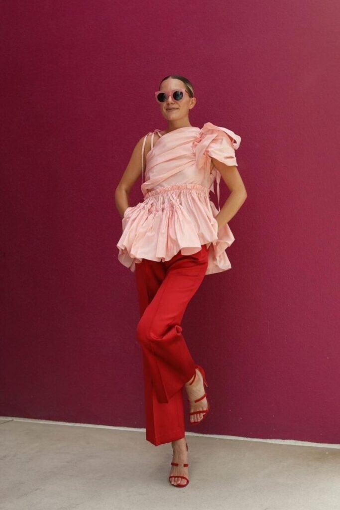 soft pink ruffled top with red tailored pants