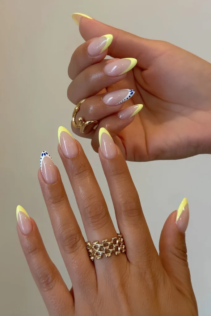 Yellow French tip nails with blue and white tip accents.jpg