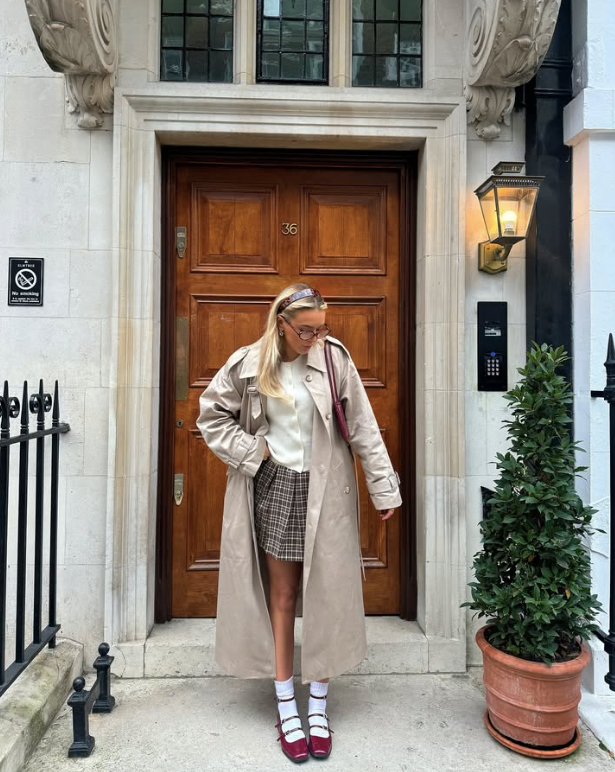 beige trench coat over a white top and plaid skirt