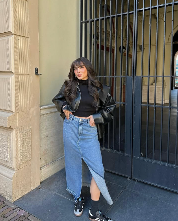 black leather jacket black turtleneck and a blue denim skirt with an asymmetrical hem