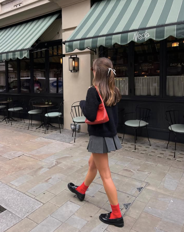 black sweater gray pleated skirt red socks and black shoes
