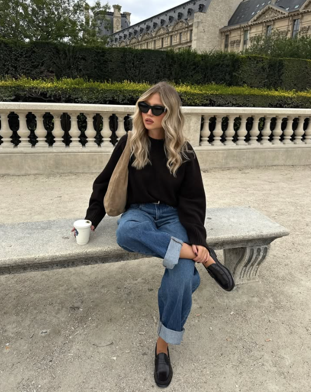 black sweater rolled up blue jeans and black loafers