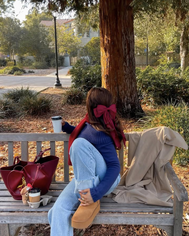 blue sweater and jeans. A beige coat and a red bag