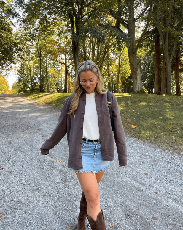 brown jacket over a white top a denim skirt and brown boots