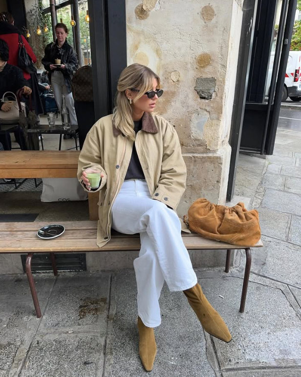 sunglasses and a beige jacket white pants and tan boots with a brown bag