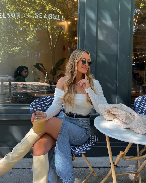 white off the shoulder top a denim skirt and knee high beige boots