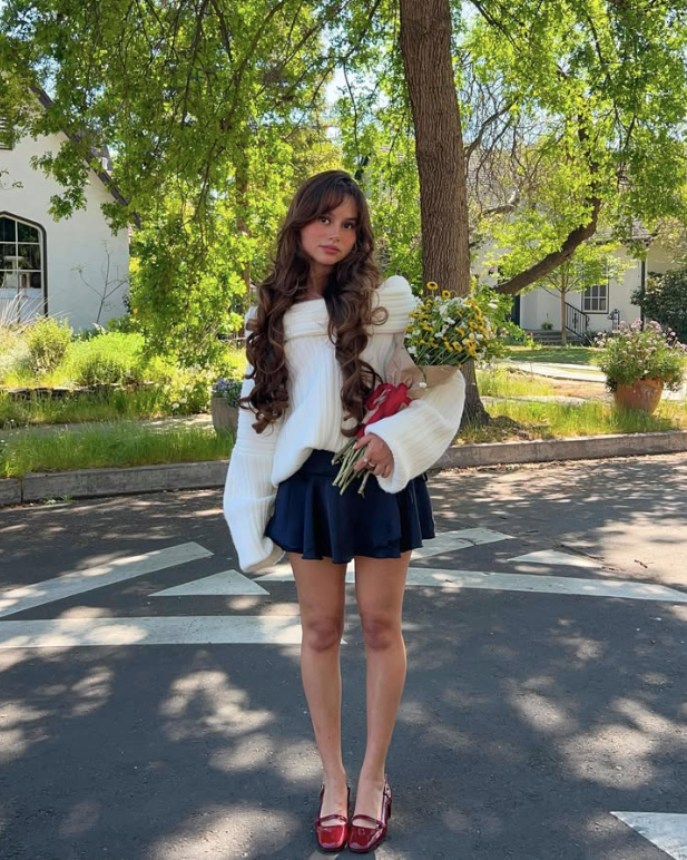 white sweater a navy skirt and red shoes