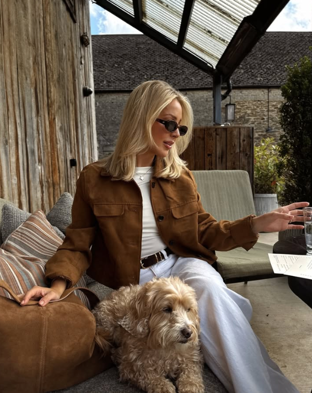 woman with blonde hair wearing sunglasses and a brown jacket